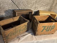Overview photo showing Coca-Cola and 7-Up wooden crates, along with plain blank crates behind them on a tabletop.