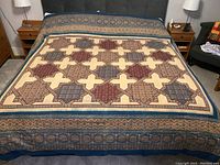 Full view of bed cover spread on a king-sized bed showing the geometric star and cross block print pattern with ornate borders