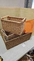 Three wicker baskets stacked on a white surface, showing different sizes and shapes.
