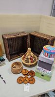 Two rectangular stacked rattan baskets, handwoven Berber Moroccan basket with lid, round wood container, four wooden coasters, three decorative storage boxes