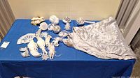 Full view of all items on blue tablecloth including tree skirt and various white and silver ornaments
