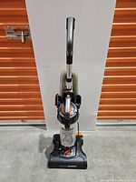 Front view of the upright vacuum showing the handle, dust canister, and base brush head labeled 'PowerSpeed'.