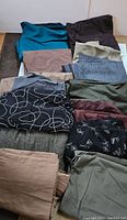 Photo of assorted folded fabric pieces in a box, showing variety of colors and textures including solid colors and patterns.