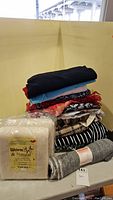 Stack of assorted fabric pieces in various colors and patterns with two packages of cotton batting in front.
