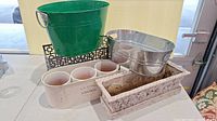 Green metal bucket, silver metal oval planter, four small white pottery pots in rectangular white planter, large distressed white rectangular planter.