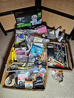 Full box showing assorted hardware components, hand tools, and NOMA LED light bulbs.