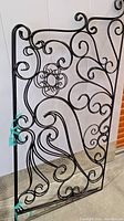 Full view of metal headboard showing intricate spiral and scroll metalwork design with hinges visible on side.