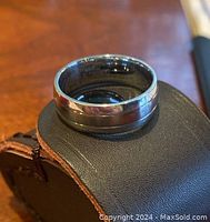 Ring resting on leather pad, top-down view showing profile and finish.