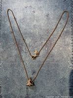 Photo of the full rose gold necklace chain with Christmas tree pendant laid flat on textured surface.