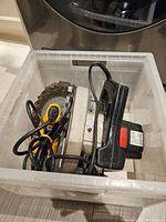 Sears Craftsman circular saw and Black & Decker drill packed in plastic bin showing power cords and circular saw blade.