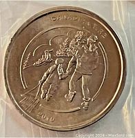 Close-up of a Canadian Tire 2010 Tobogganing coin showing detailed tobogganing design and text.