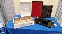 Wooden 'General Store' box with compartments, red and black lacquer trays on blue table