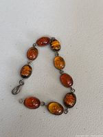 Close-up view of the amber bracelet showing oval amber stones with silver bezel setting and lobster clasp.