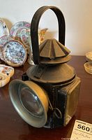 Front side angle showing metal case, brass bezel, and glass lens of the lantern.