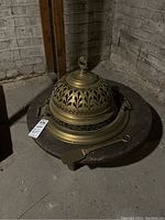 Full view of the brazier with brass dome cover and wooden base, showing side handles and the rasera paddle lying next to it.