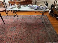 Full view of rug under folding table showing overall pattern and wear.