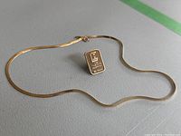 Full serpentine chain with spring ring clasp laid out with lapel pin