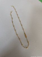 Full view of gold bead chain necklace laid on white surface