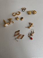 Overall assortment of earrings, ring and cufflinks on white background