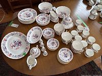 Full service layout on table showing plates, bowls, cups, saucers, teapot, cream jug, sugar bowl, shakers, gravy boat, serving dishes and platter