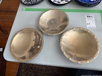 Three shallow sterling bowls displayed side by side on table
