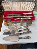 Photo of entire set of sterling silver serving utensils including carving knife, fork, sharpening steel, three cake servers, and vintage glass salt and pepper shakers with sterling lids and small jar with sterling lid