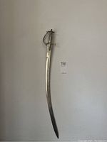 Full sword with curved blade hanging against wall showing overall length and form.