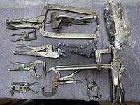 Top-down view of the welding clamps spread out on cloth surface showing full set arrangement.