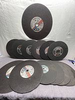 Front view of all 14 steel chop blades laid out showing various sizes and brand labels