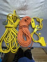 Photo of two coiled heavy duty extension cords (yellow and orange) alongside two yellow portable GFCI units.