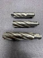 Three spiral flute annular cutters laid on fabric, showing varied sizes and shanks.