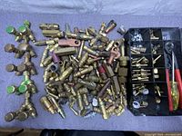 Top down view of brass fittings, valves with green handles, and various connectors piled on cloth.