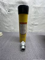 Front view of yellow cylinder with black cap and quick-coupler at base