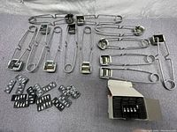 Full lot of flint striker safety pins arranged on surface alongside multiple packs of black flint refills and an open pack showing small rectangular flints inside.