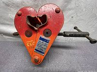 Front view of the orange JET beam clamp showing the clamp jaws and capacity tag with model and serial number.