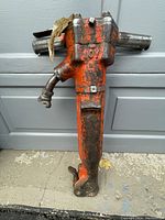 Full view of the orange-painted Joy hydraulic jackhammer showing body, handles, and attachment point for hydraulic hose.