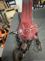 Top view showing red paint body with embossed 'MODEL 1 1/2 PULLER' and hooks connected to heavy chain.