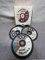 Photo showing the pack box and three sample cutoff wheels, highlighting the product branding and packaging.