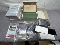Overview of all items for sale including multiple stacks of welding face mask glass, sealed packages, and some sandpaper sheets.