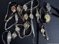 Full lot showing 13 ladies vintage watches arranged on black background, varying styles with metal and leather bands.