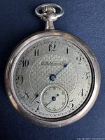 Front view of the gold-tone vintage pocket watch with black Arabic numerals and textured dial.