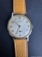 Front view of vintage Solar Swiss made wristwatch with tan leather strap, visible wear and scratches on watch face.