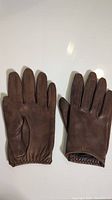 Pair of brown Danier leather gloves laid flat with palms facing down, visible elastic wrist detail