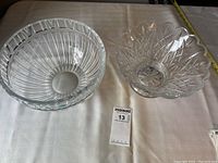 Two large crystal bowls side by side on a white cloth, showing the overall size and form of both bowls.