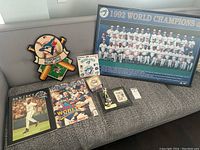 Full lot including framed team poster, clock, program books, Joe Carter card, trophy figurine, and stickers.