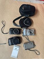 Four cameras (two front-facing) and two cases on tabletop