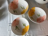 Top view showing the three ceramic bowls with floral patterns in yellow and pink on the interior.
