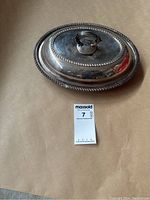Top view of oval silver plated covered dish, showing beaded edge and handle