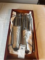 Photo of the full utensil set in wooden box with cloth lining, showing the handles and storage layout.