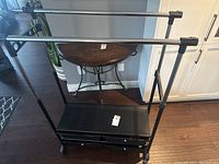 Full view of the storage rack showing top horizontal clothing rod and middle shelf surface